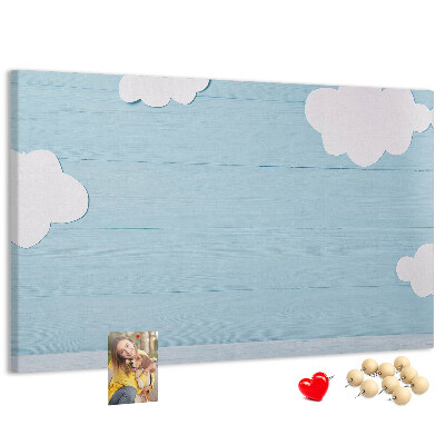 Pizarra de corcho con diseño de cielo con nubes sobre fondo de madera