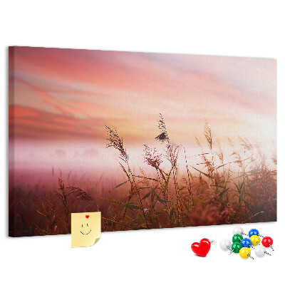 Tablero de anuncios con diseño de puesta de sol sobre un campo de hierba