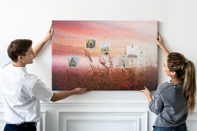 Tablero de anuncios con diseño de puesta de sol sobre un campo de hierba