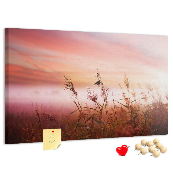 Tablero de anuncios con diseño de puesta de sol sobre un campo de hierba