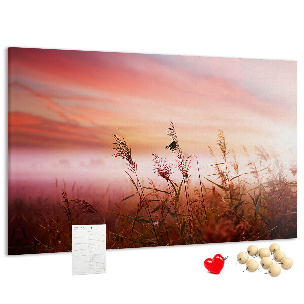Tablero de anuncios con diseño de puesta de sol sobre un campo de hierba