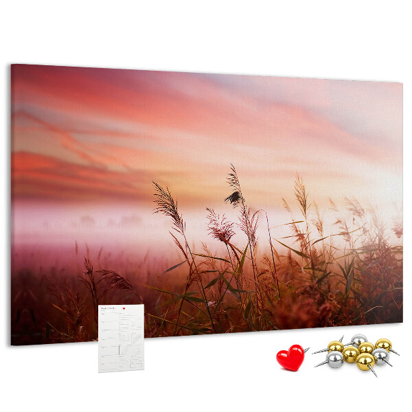 Tablero de anuncios con diseño de puesta de sol sobre un campo de hierba