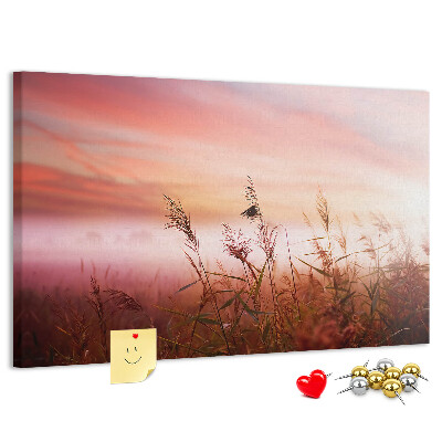 Tablero de anuncios con diseño de puesta de sol sobre un campo de hierba