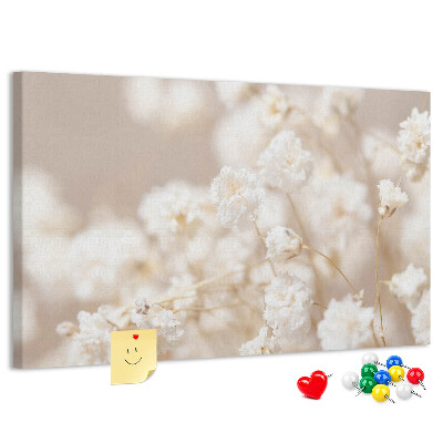 Tablero de corcho decorado con delicadas flores blancas sobre un fondo neutro