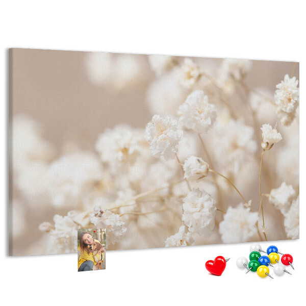 Tablero de corcho decorado con delicadas flores blancas sobre un fondo neutro