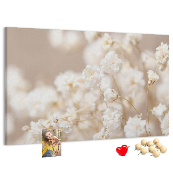 Tablero de corcho decorado con delicadas flores blancas sobre un fondo neutro
