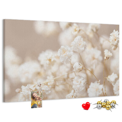 Tablero de corcho decorado con delicadas flores blancas sobre un fondo neutro