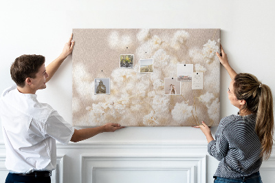 Tablero de corcho decorado con delicadas flores blancas sobre un fondo neutro