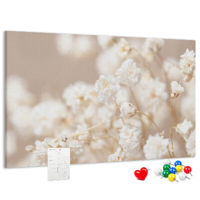 Tablero de corcho decorado con delicadas flores blancas sobre un fondo neutro