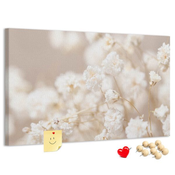 Tablero de corcho decorado con delicadas flores blancas sobre un fondo neutro
