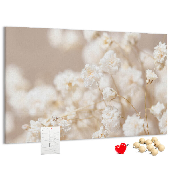 Tablero de corcho decorado con delicadas flores blancas sobre un fondo neutro