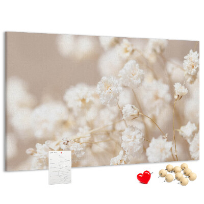 Tablero de corcho decorado con delicadas flores blancas sobre un fondo neutro