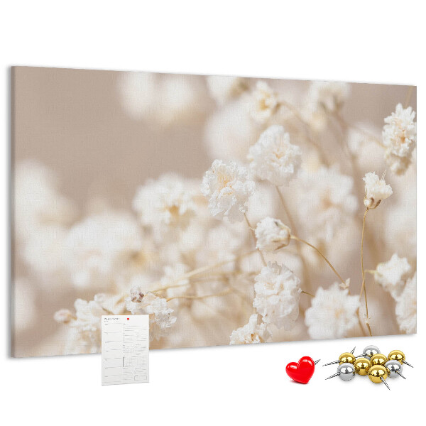 Tablero de corcho decorado con delicadas flores blancas sobre un fondo neutro