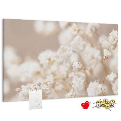 Tablero de corcho decorado con delicadas flores blancas sobre un fondo neutro