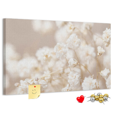 Tablero de corcho decorado con delicadas flores blancas sobre un fondo neutro