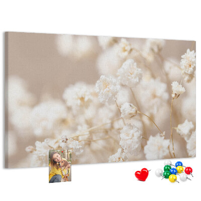 Tablero de corcho decorado con delicadas flores blancas sobre un fondo neutro