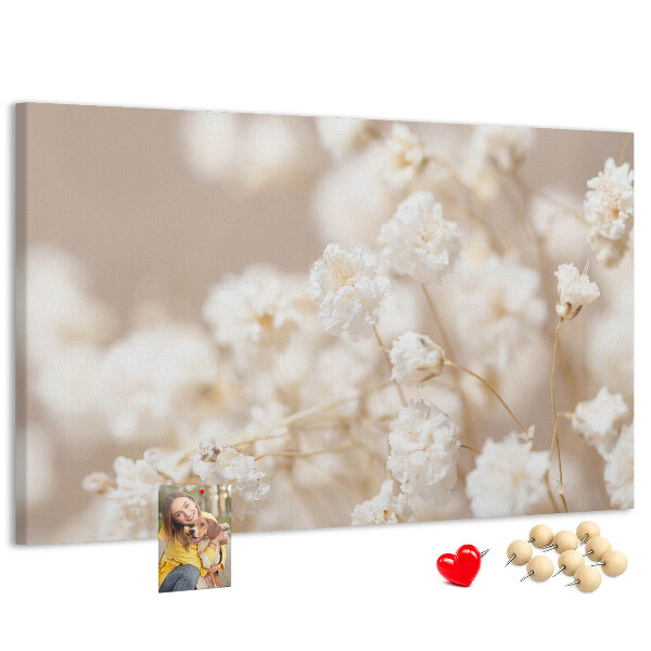 Tablero de corcho decorado con delicadas flores blancas sobre un fondo neutro
