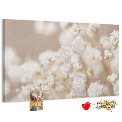 Tablero de corcho decorado con delicadas flores blancas sobre un fondo neutro