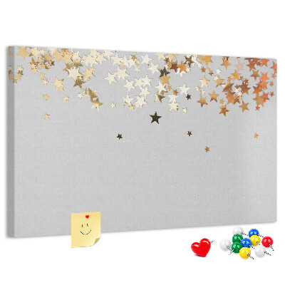 Tablero de corcho decorativo con diseño de estrellas doradas sobre fondo gris
