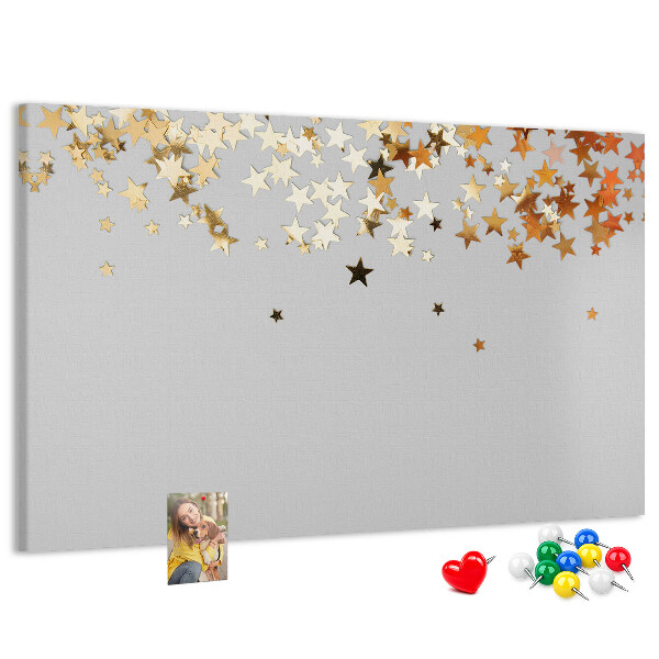 Tablero de corcho decorativo con diseño de estrellas doradas sobre fondo gris