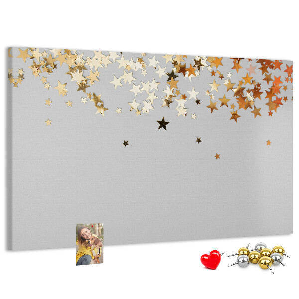 Tablero de corcho decorativo con diseño de estrellas doradas sobre fondo gris