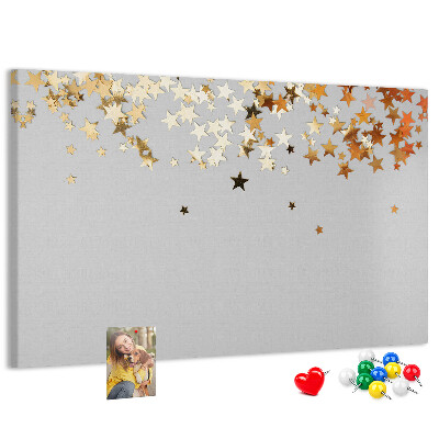 Tablero de corcho decorativo con diseño de estrellas doradas sobre fondo gris