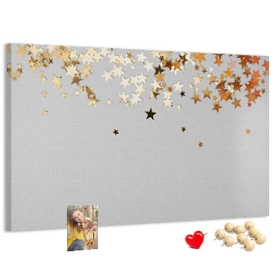 Tablero de corcho decorativo con diseño de estrellas doradas sobre fondo gris