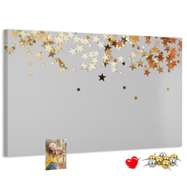 Tablero de corcho decorativo con diseño de estrellas doradas sobre fondo gris