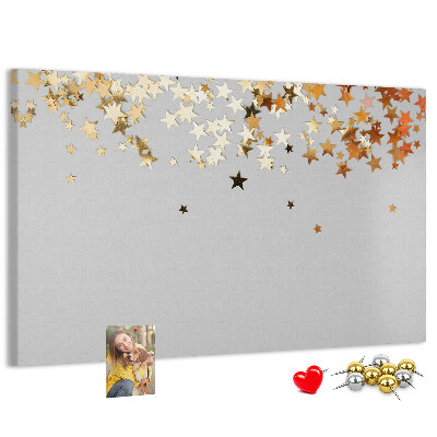 Tablero de corcho decorativo con diseño de estrellas doradas sobre fondo gris
