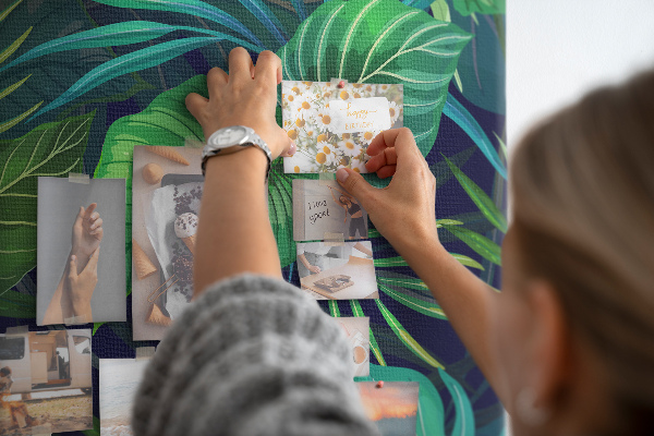 Tablero de corcho decorativo con diseño de hojas tropicales sobre fondo oscuro