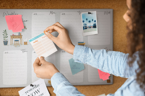 Pizarra de corcho con diseño de agenda semanal y detalles de plantas