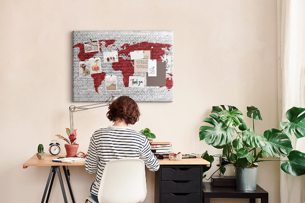Tablero de corcho decorativo con diseño de contorno rojo del mundo sobre pared de ladrillos
