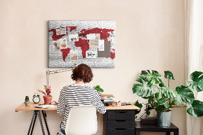 Tablero de corcho decorativo con diseño de contorno rojo del mundo sobre pared de ladrillos