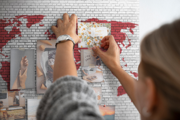 Tablero de corcho decorativo con diseño de contorno rojo del mundo sobre pared de ladrillos