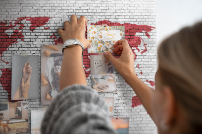 Tablero de corcho decorativo con diseño de contorno rojo del mundo sobre pared de ladrillos