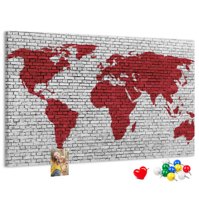 Tablero de corcho decorativo con diseño de contorno rojo del mundo sobre pared de ladrillos