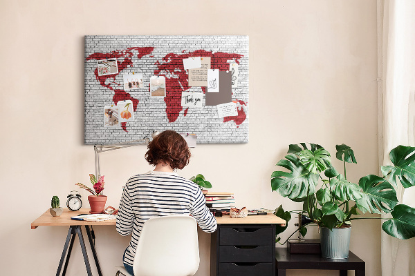 Tablero de corcho decorativo con diseño de contorno rojo del mundo sobre pared de ladrillos