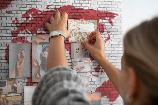 Tablero de corcho decorativo con diseño de contorno rojo del mundo sobre pared de ladrillos