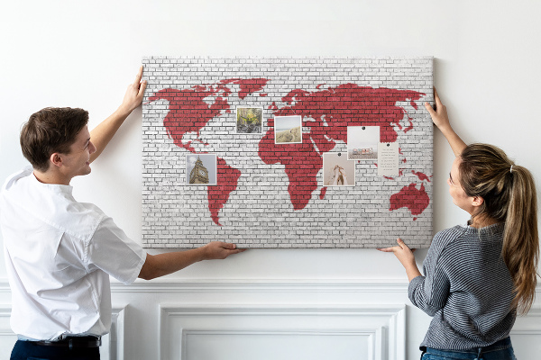 Tablero de corcho decorativo con diseño de contorno rojo del mundo sobre pared de ladrillos
