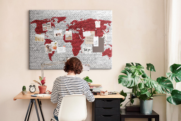 Tablero de corcho decorativo con diseño de contorno rojo del mundo sobre pared de ladrillos