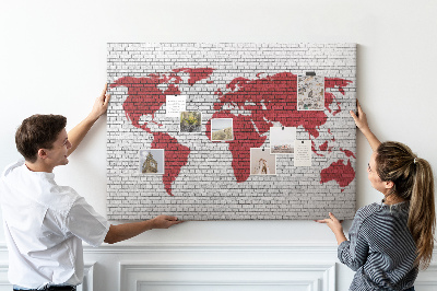 Tablero de corcho decorativo con diseño de contorno rojo del mundo sobre pared de ladrillos