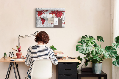 Tablero de corcho decorativo con diseño de contorno rojo del mundo sobre pared de ladrillos