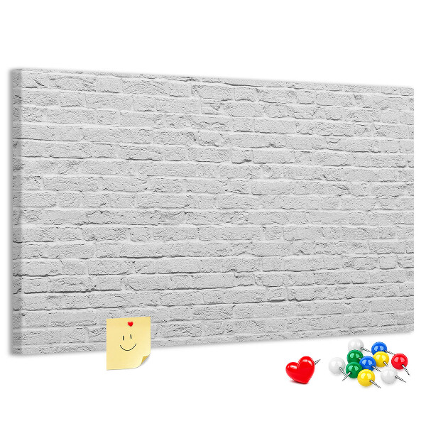 Tablero de anuncios con diseño de pared de ladrillo blanco y chinchetas de colores