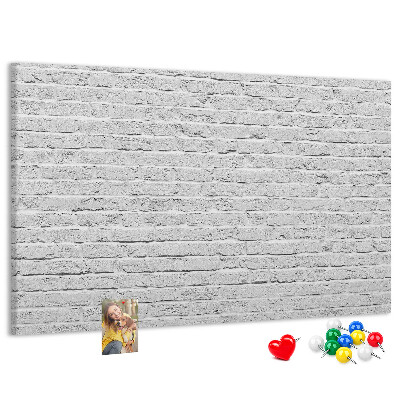 Tablero de anuncios con diseño de pared de ladrillo blanco y chinchetas de colores
