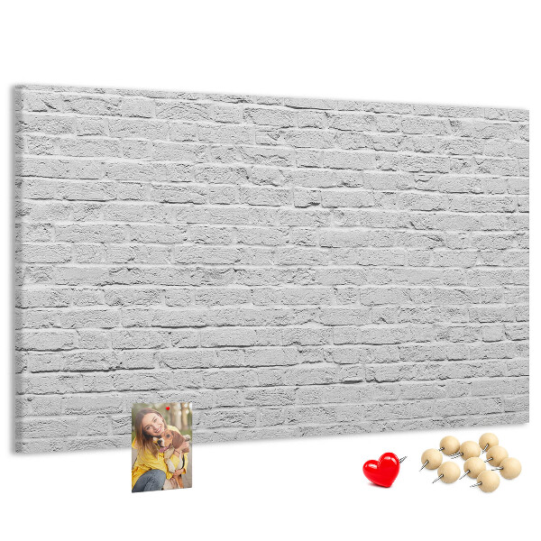 Tablero de anuncios con diseño de pared de ladrillo blanco y chinchetas de colores