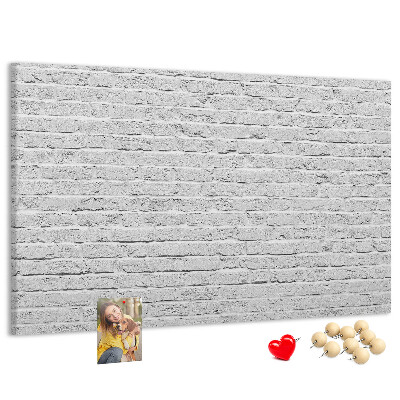 Tablero de anuncios con diseño de pared de ladrillo blanco y chinchetas de colores