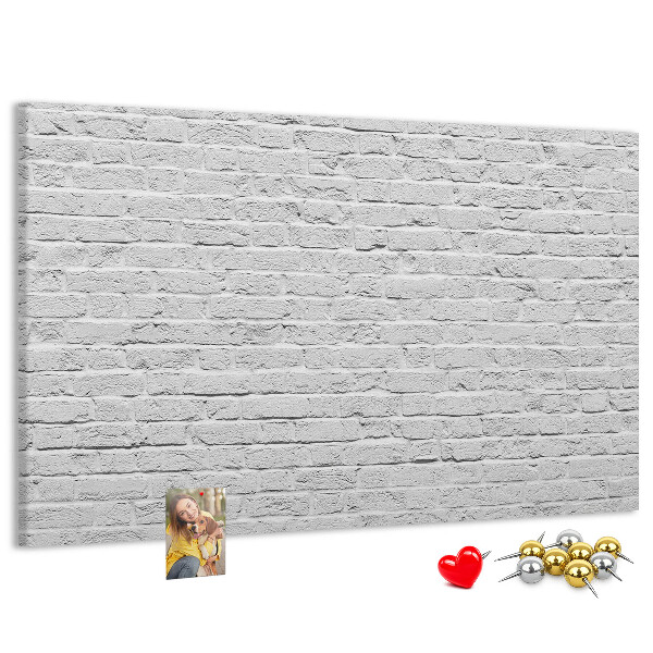 Tablero de anuncios con diseño de pared de ladrillo blanco y chinchetas de colores