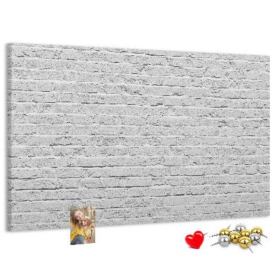 Tablero de anuncios con diseño de pared de ladrillo blanco y chinchetas de colores