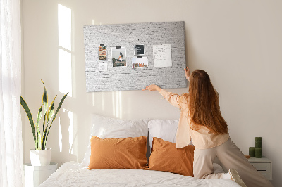 Tablero de anuncios con diseño de pared de ladrillo blanco y chinchetas de colores