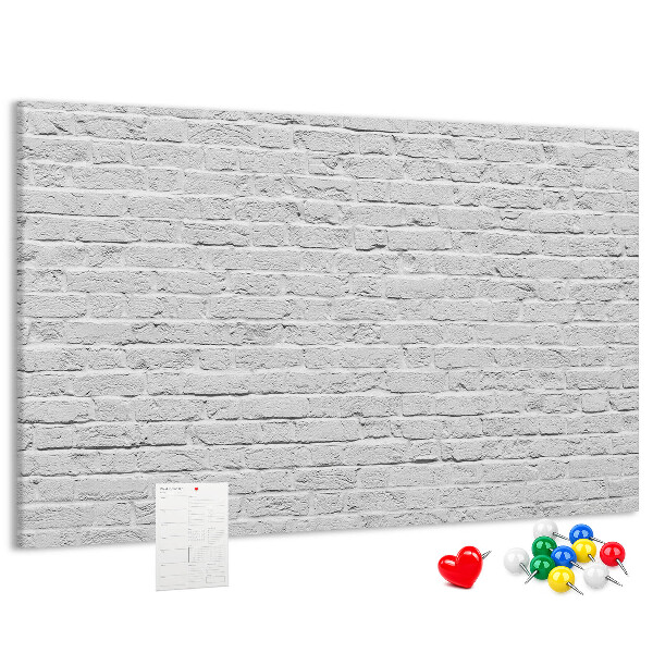 Tablero de anuncios con diseño de pared de ladrillo blanco y chinchetas de colores